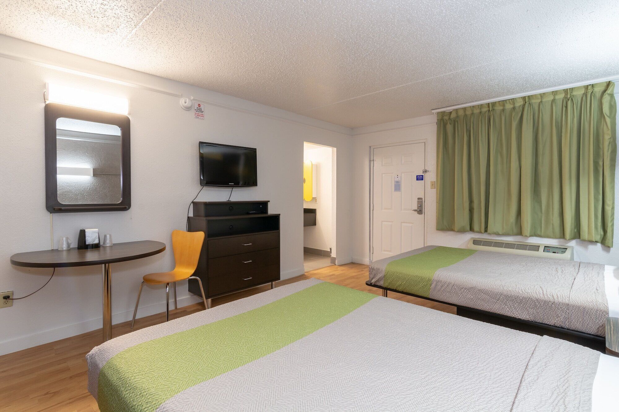 A hotel room with two beds, a TV, a desk, and a chair.
