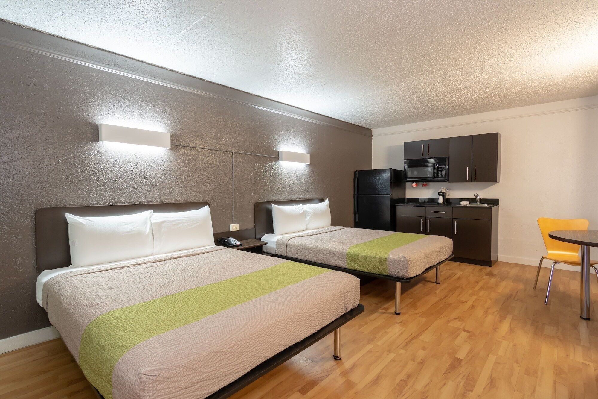 Una habitación de hotel compacta con dos camas individuales, una kitchenette y un pequeño comedor.