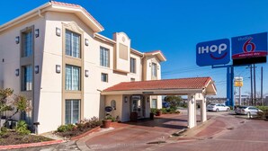 A hotel with a covered entrance, a sign for 'IHOP 6 extended stay', and a clear blue sky. - Studio 6 Fort Worth, TX - West Medical Center (Fort Worth)
