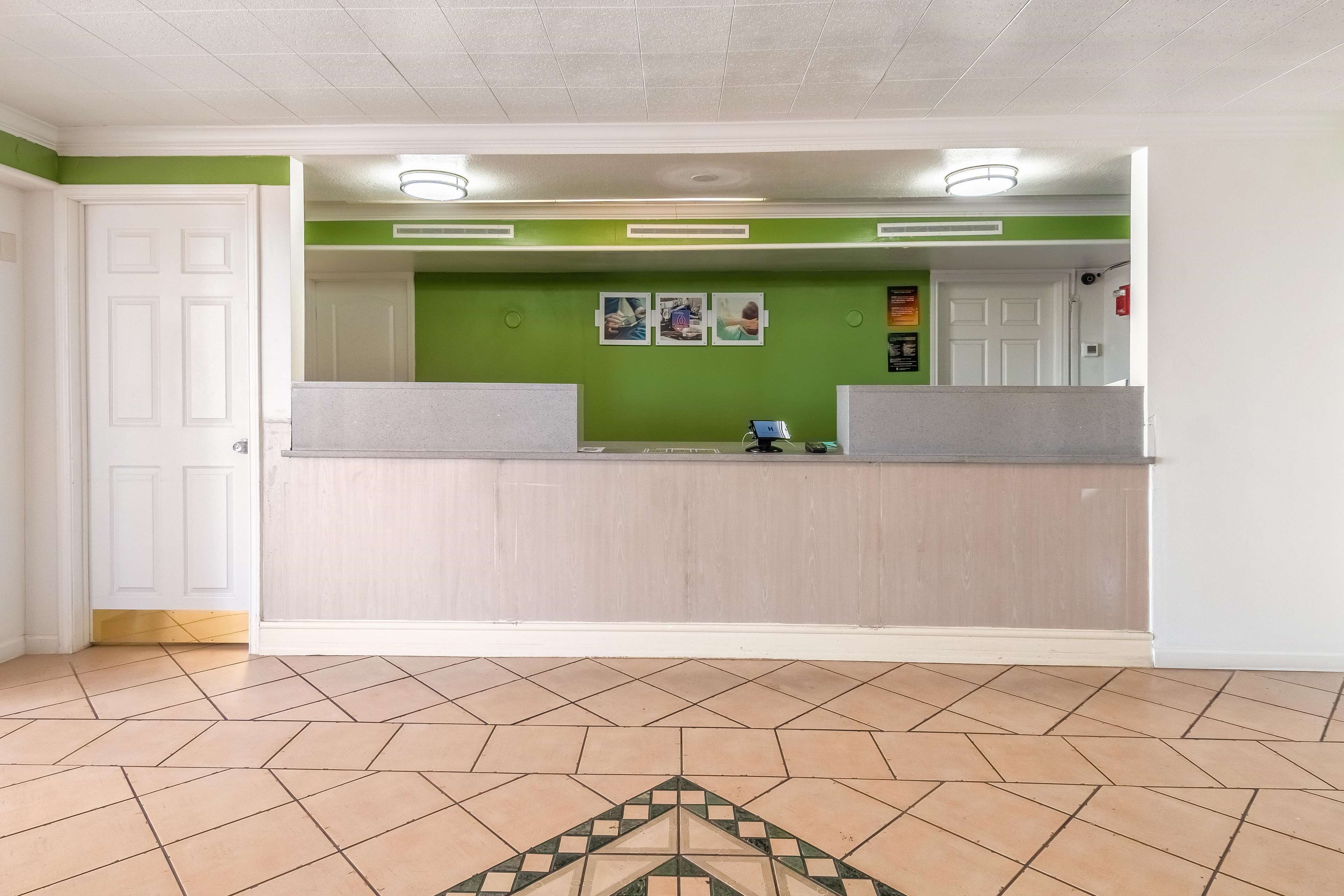 A reception area with a green wall, a reception desk, and a tiled floor.