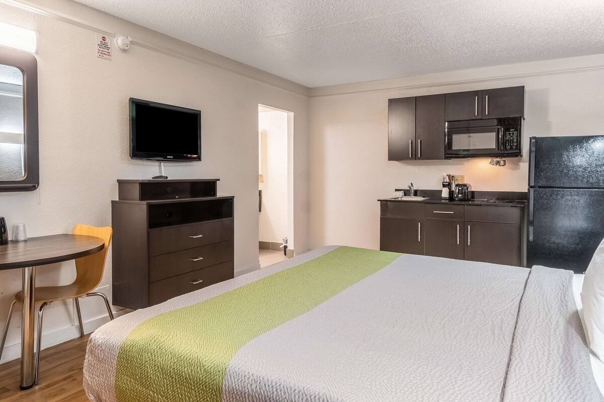Una habitación de hotel con una cama, un escritorio, un televisor, un microondas y un refrigerador.