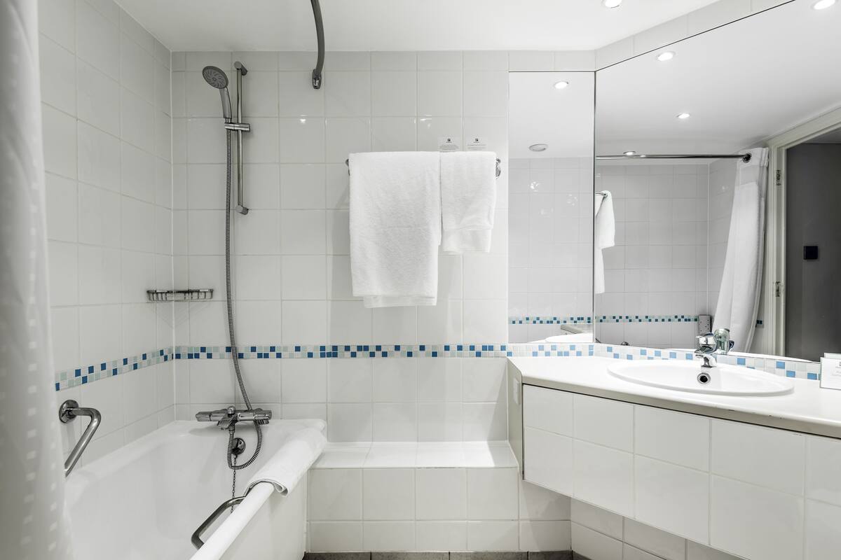 A modern bathroom with a bathtub, a shower, a sink, and a mirror.