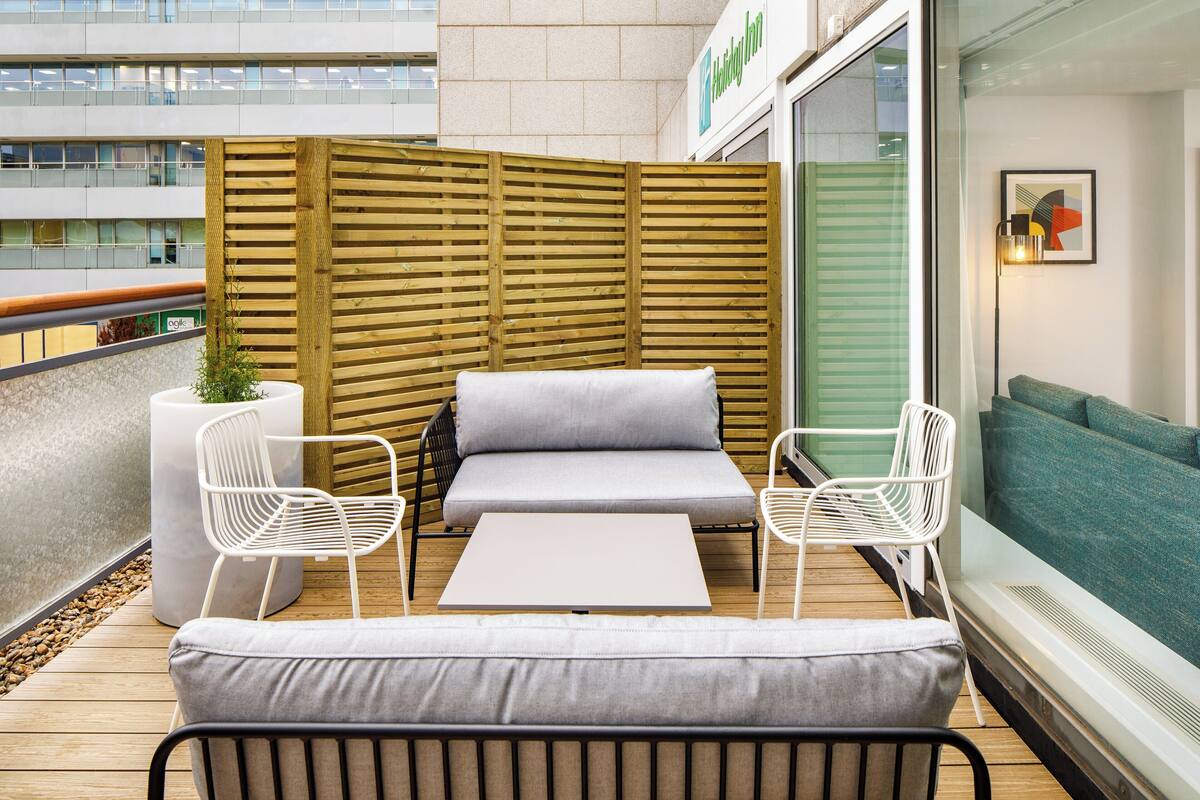 A modern outdoor seating area with a sofa, two chairs, and a table.