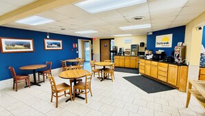 A breakfast area with wooden tables and chairs, a counter with a coffee machine, and wall-mounted pictures.