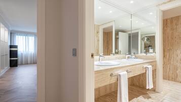 Un baño moderno con dos lavamanos, un espejo grande y suelo de madera.
