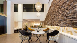 A modern dining area with a stone accent wall, a chandelier, and a central table with chairs. - Eurostars Gran Hotel Lugo (Lugo)
