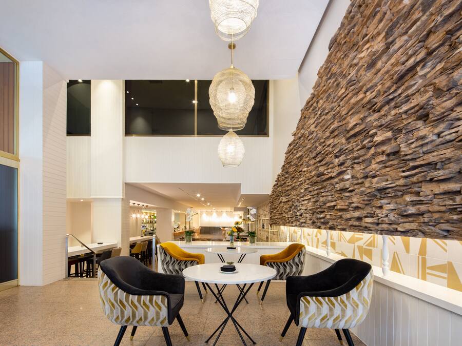 A modern dining area with a stone accent wall, a chandelier, and a central table with chairs.