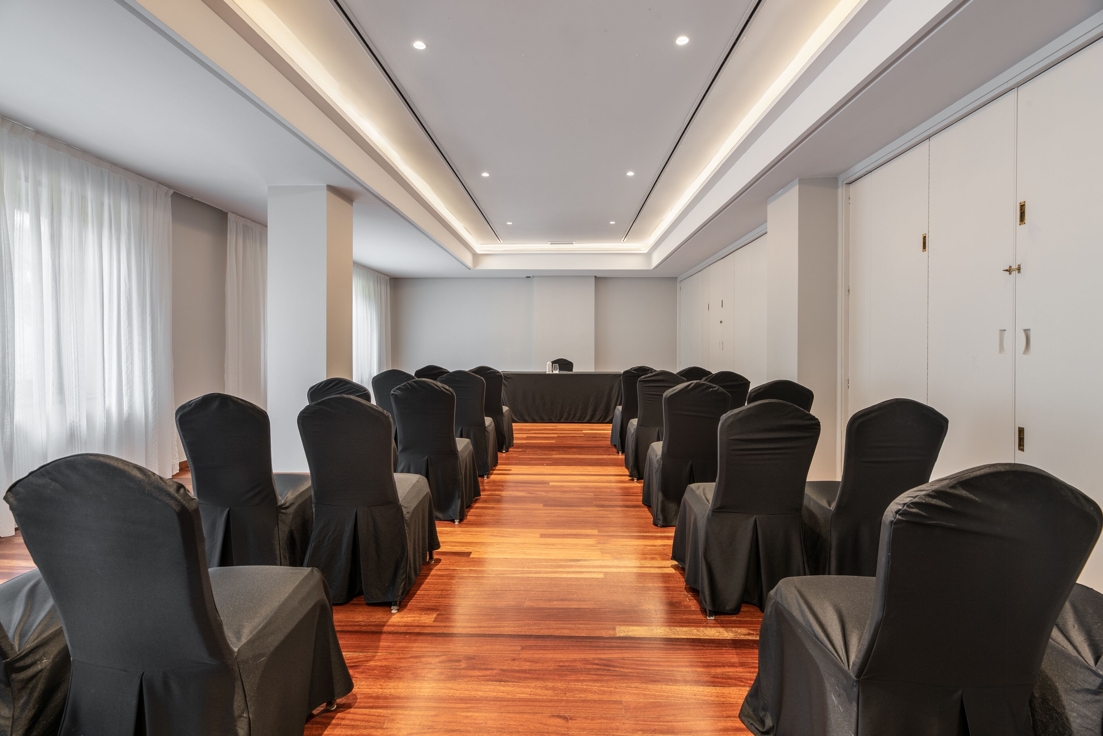 Un salón de conferencias con filas de sillas, un atril y una larga mesa.