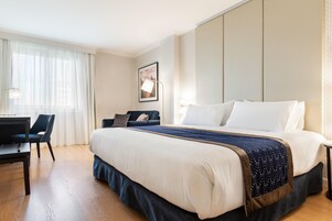 Una habitación de hotel con una cama grande, un escritorio y una silla.