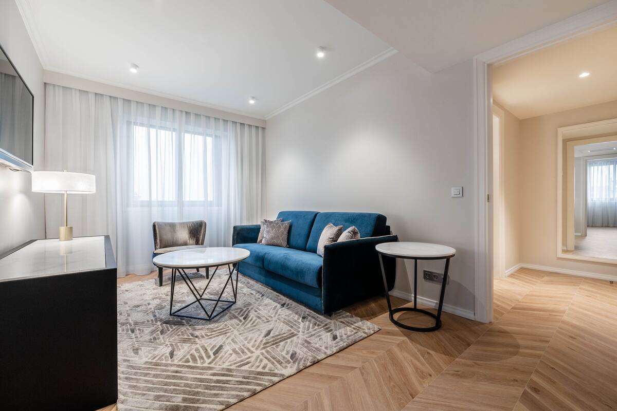 A modern living room with a blue sofa, two round tables, and a large mirror.