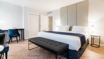 Una habitación de hotel moderna con una cama grande, un banco, un escritorio y una silla.
