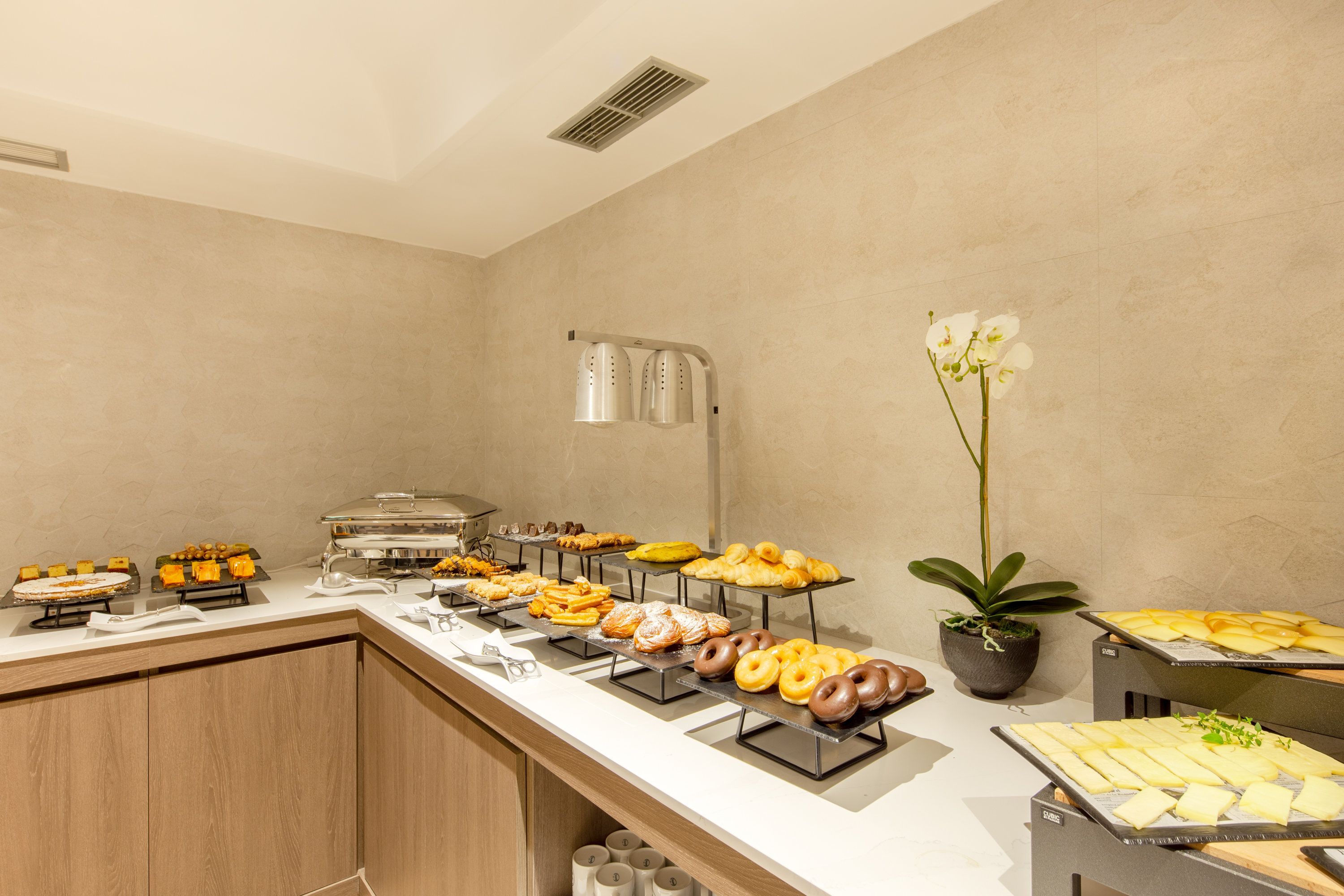 A buffet with various food items, a coffee station, and a potted plant.