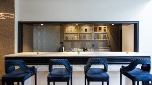 A bar area with a marble countertop, blue upholstered chairs, and a tiled backsplash with bottles. - Eurostars Gran Hotel Lugo (Lugo)