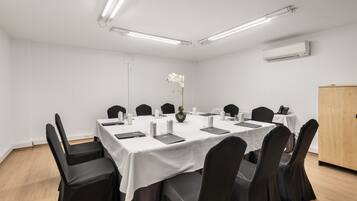 A conference room with a white table, black chairs, and a small orchid on the table.