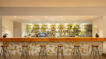 A bar area with a wooden counter, multiple stools, and shelves stocked with bottles.