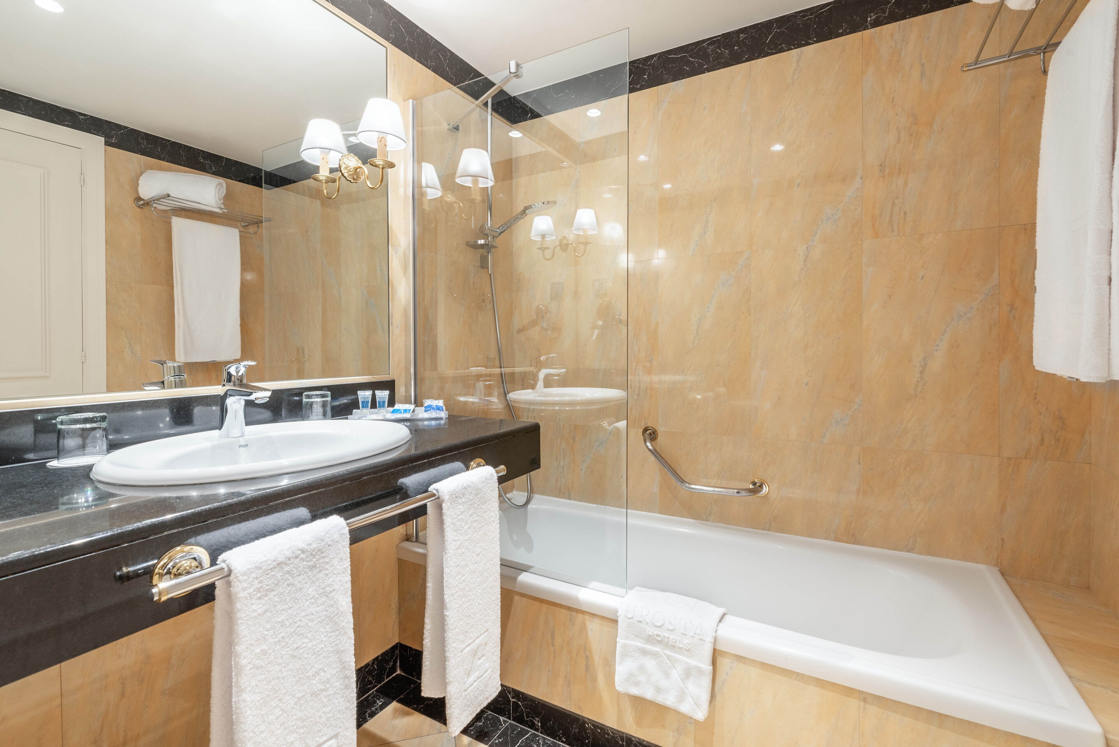 A modern bathroom with a large mirror, a sink, a bathtub, and a glass-enclosed shower area.