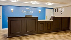 A reception desk with a blue wall and a sign that reads "Baymont Inn & Suites." - Baymont by Wyndham Jacksonville Orange Park (Jacksonville)