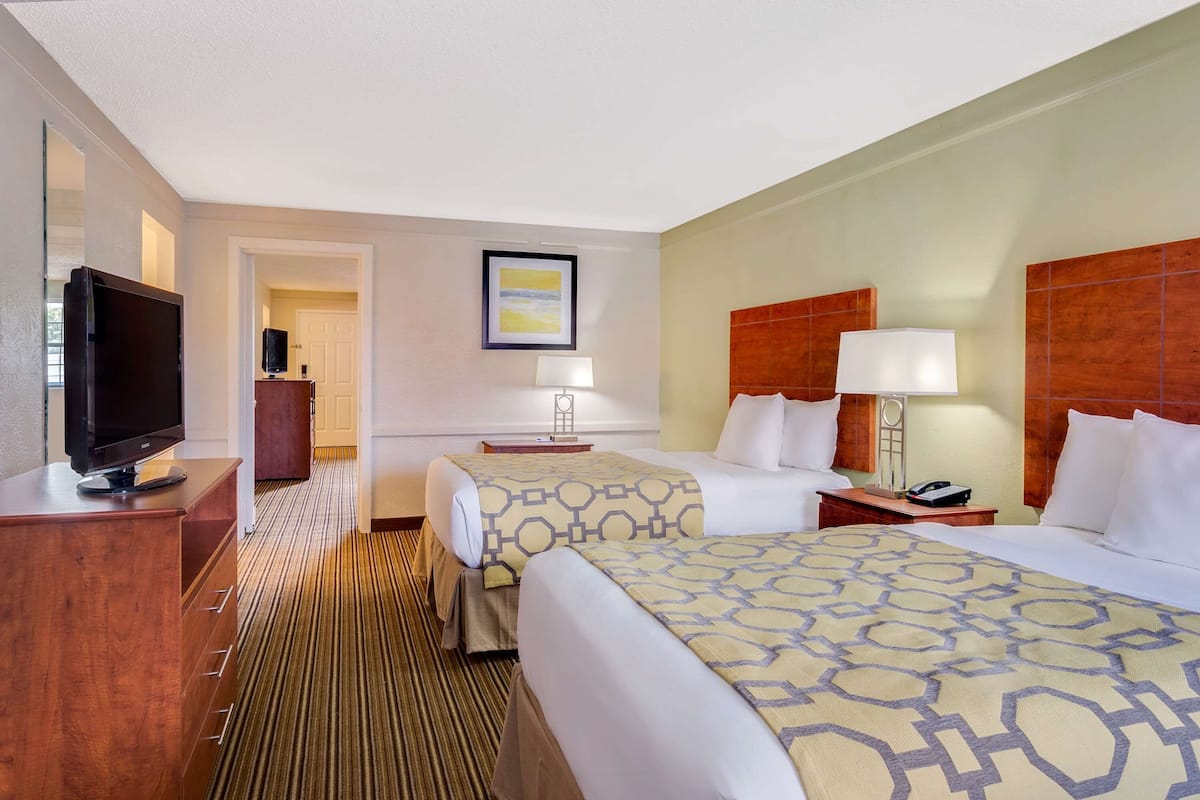 Une chambre d’hôtel avec deux lits, une télévision, un bureau et une chaise.