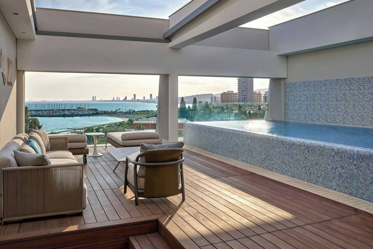 A rooftop terrace with a pool, seating area, and a view of the city skyline.