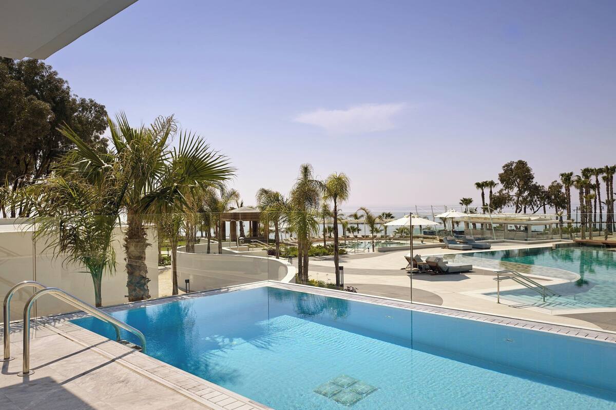 A pool area with clear blue water, palm trees, and lounge chairs.