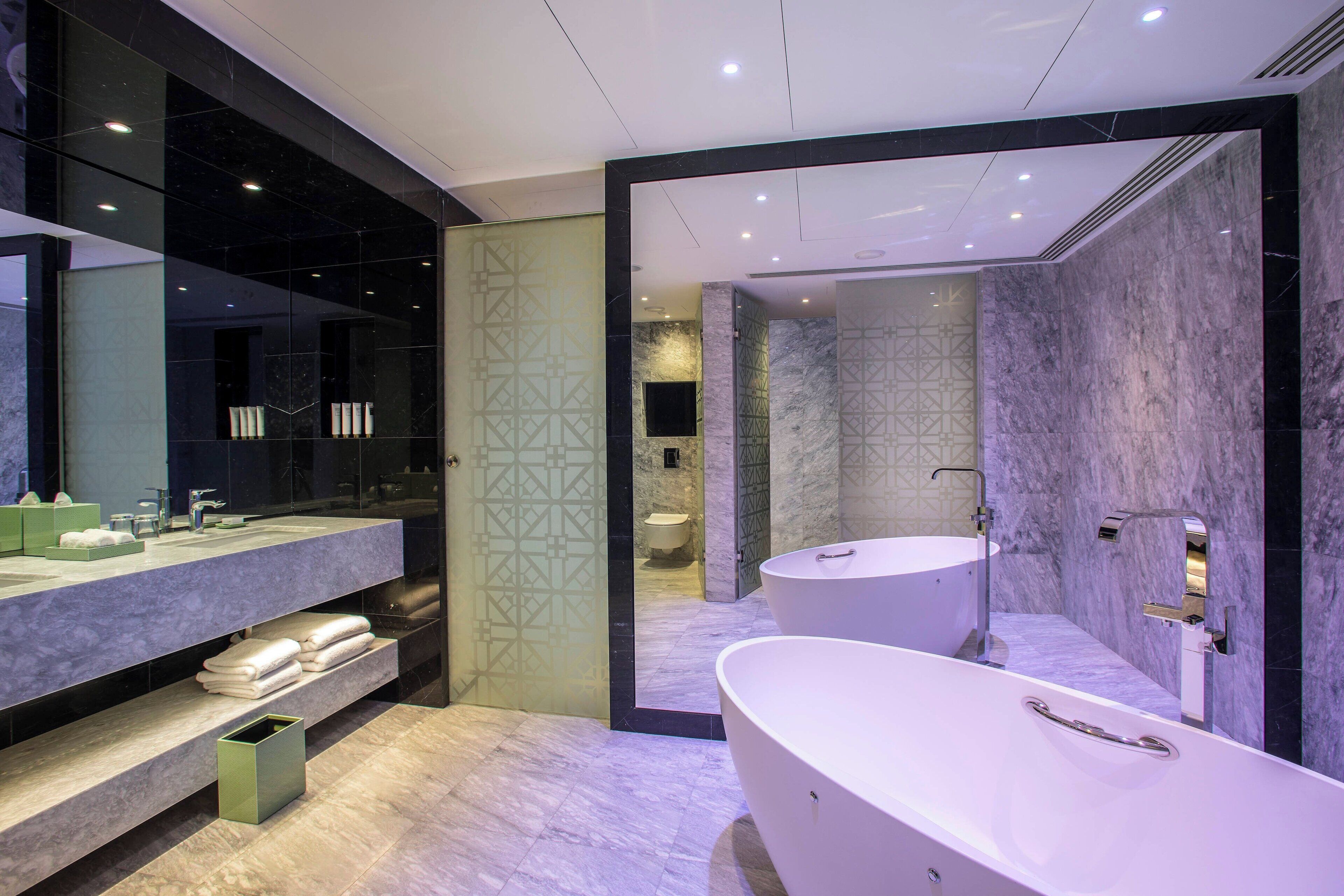 Un baño moderno con una bañera grande, un lavabo independiente y un tocador con espejo.