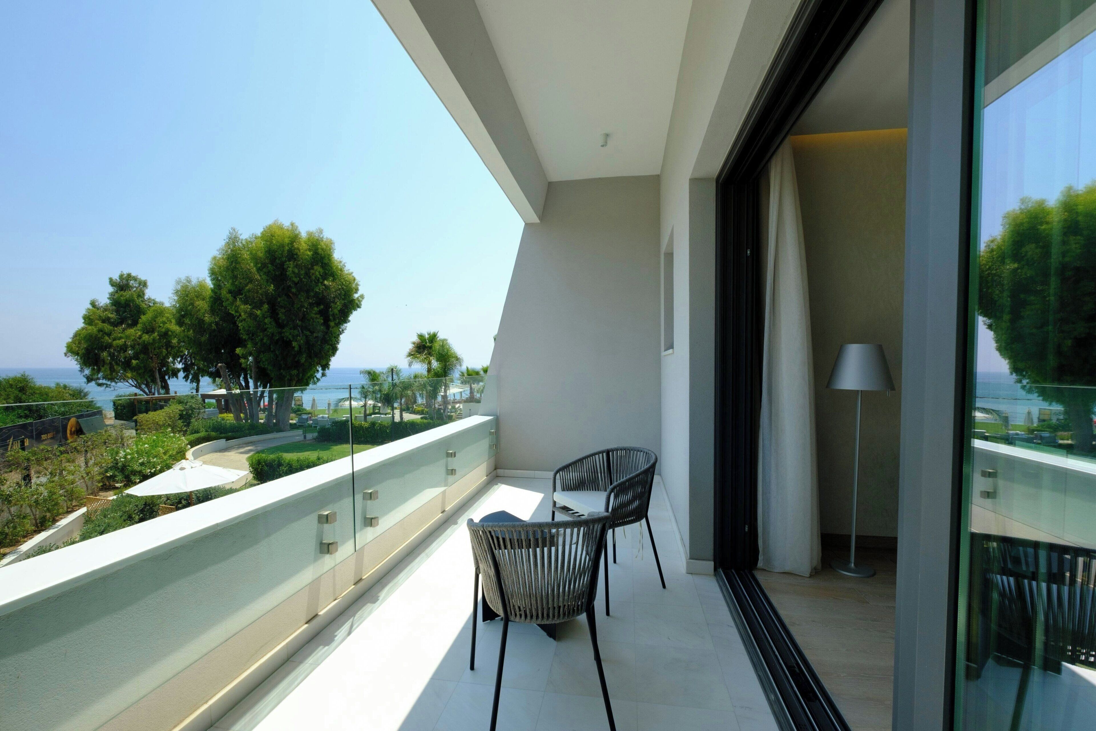 A balcony with two chairs, a table, and a lamp.
