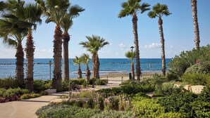 A coastal garden with palm trees, a pathway, and a view of the sea. - Parklane, a Luxury Collection Resort & Spa, Limassol (Limassol)