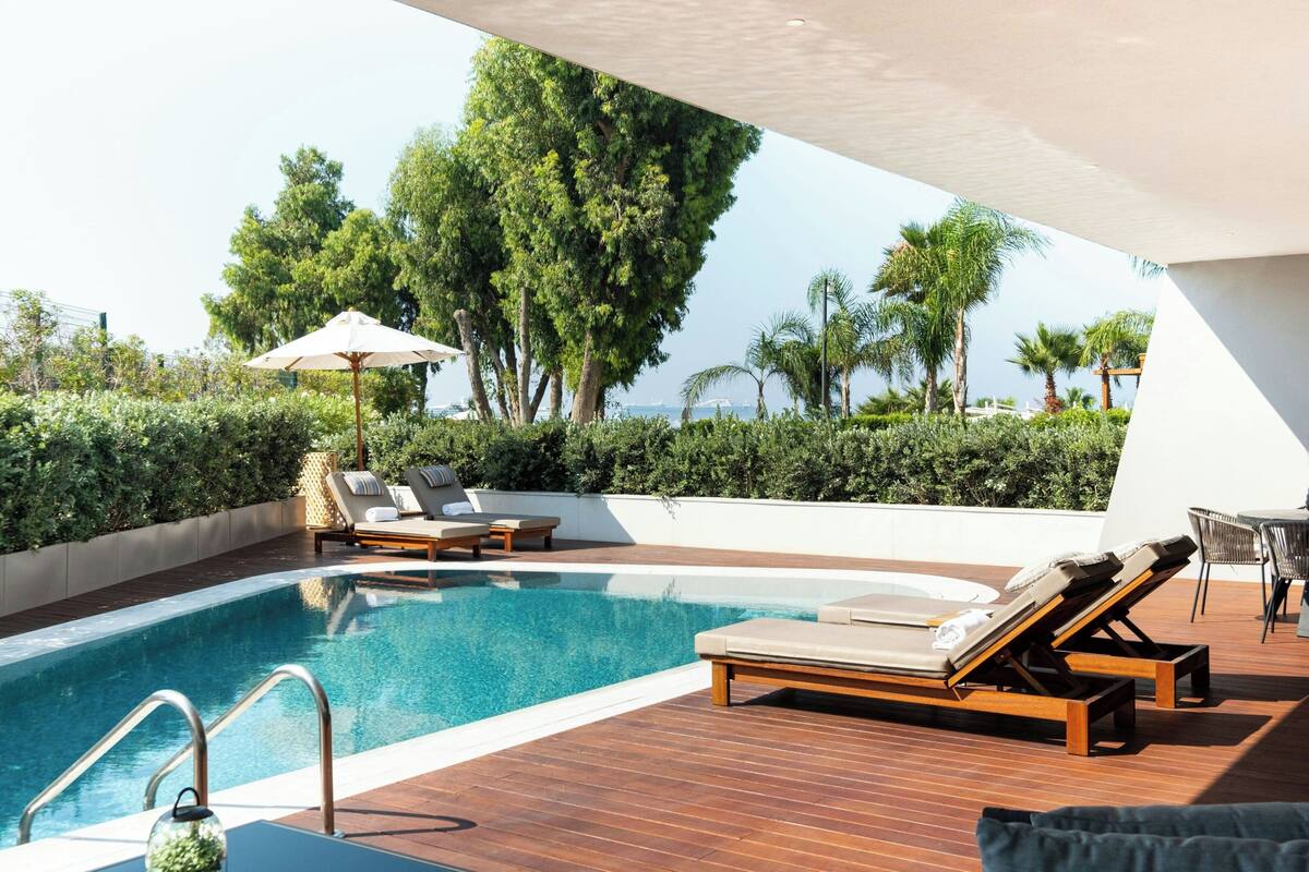 A rooftop pool area with lounge chairs, a small table, and a view of the sea.
