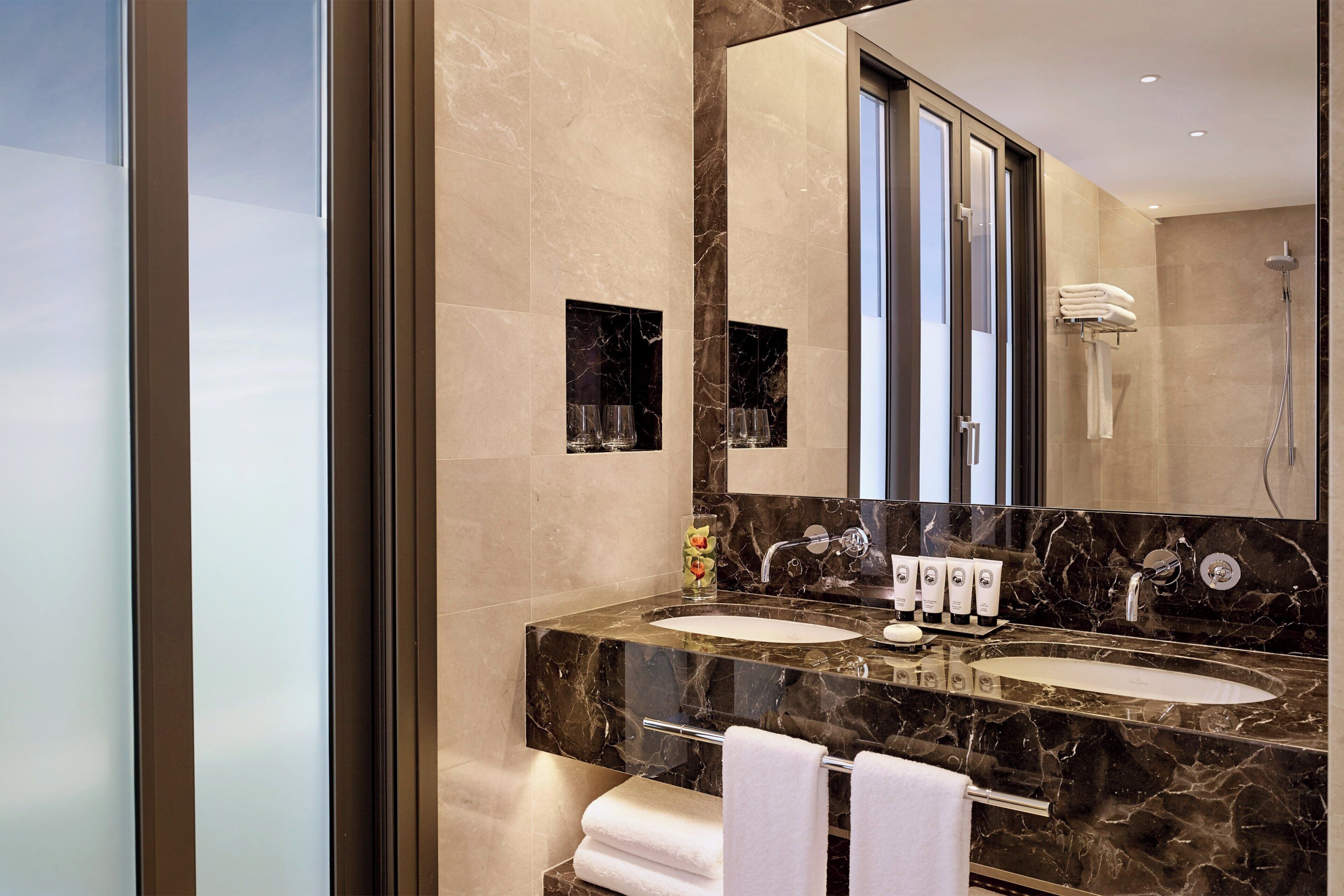 Een moderne badkamer met twee wastafels, een grote spiegel en een douche.
