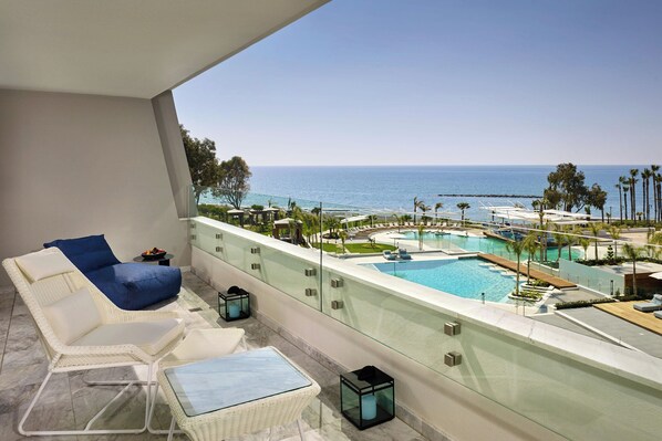 A balcony with a view of a pool and the ocean.