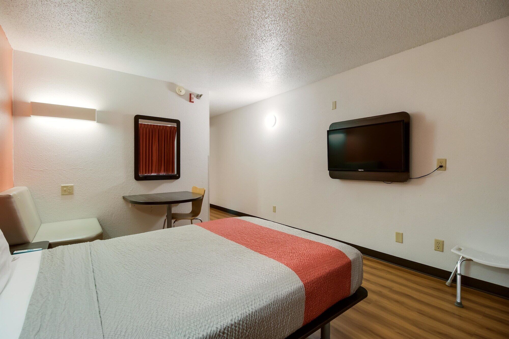 A hotel room with a bed, a desk, a chair, a television, and a window with curtains.