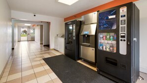 Pasillo de hotel con máquina expendedora, refrigerador y microondas.