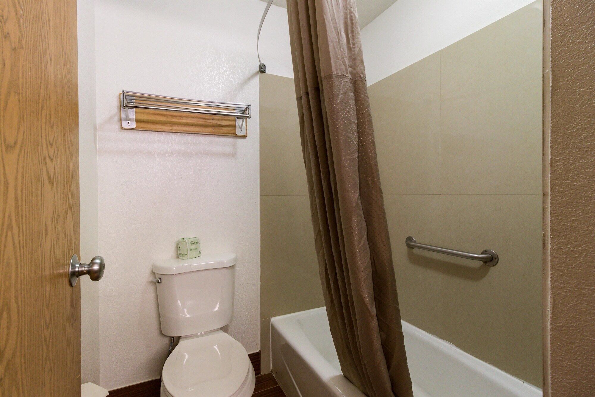 Een badkamer met een toilet, een douchegordijn en een handgreep.
