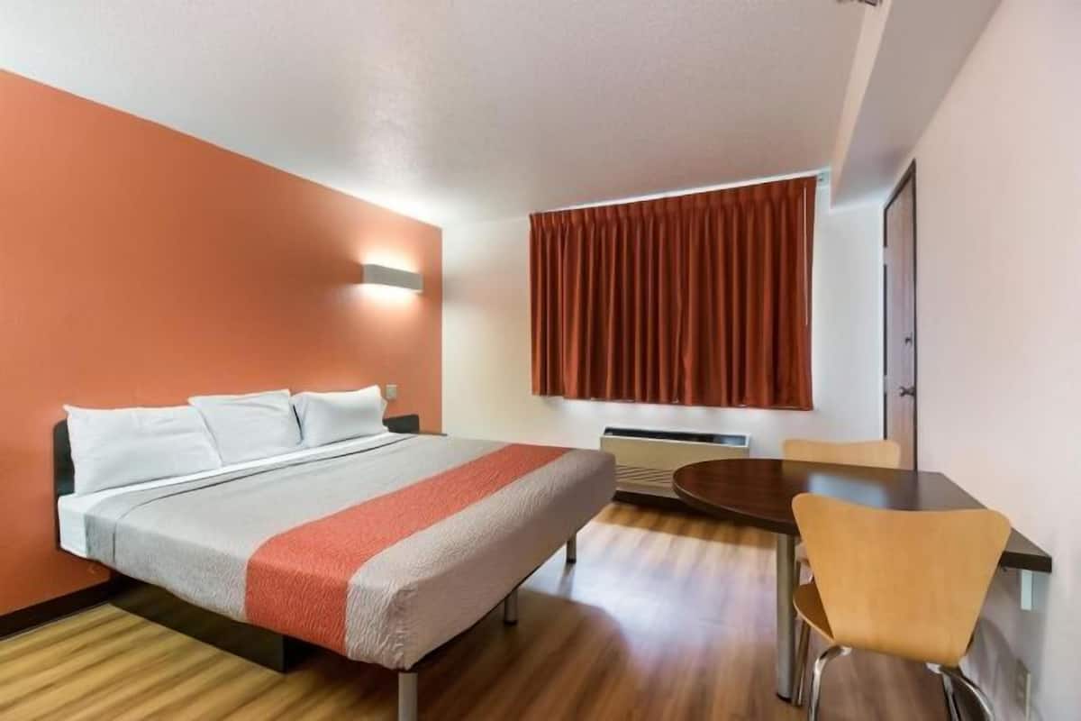 A hotel room with a bed, a dining table, and a chair.