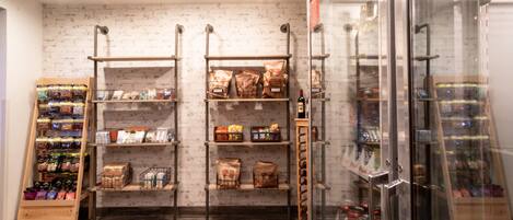 L’intérieur d’un magasin présente des étagères remplies de divers produits emballés, un présentoir de boissons en bouteille et un rayon réfrigéré avec une façade en verre.