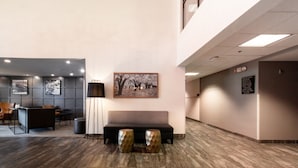 A modern lobby with a reception desk, seating area, and a large wall-mounted painting.