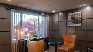 A room with two leather chairs, a small round table, a potted plant, and a framed picture on the wall.