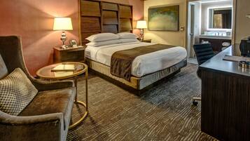 A hotel room with a bed, a desk, a chair, a round table, and a sofa.