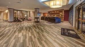 A hotel lobby with a reception desk, seating area, and a patterned floor.