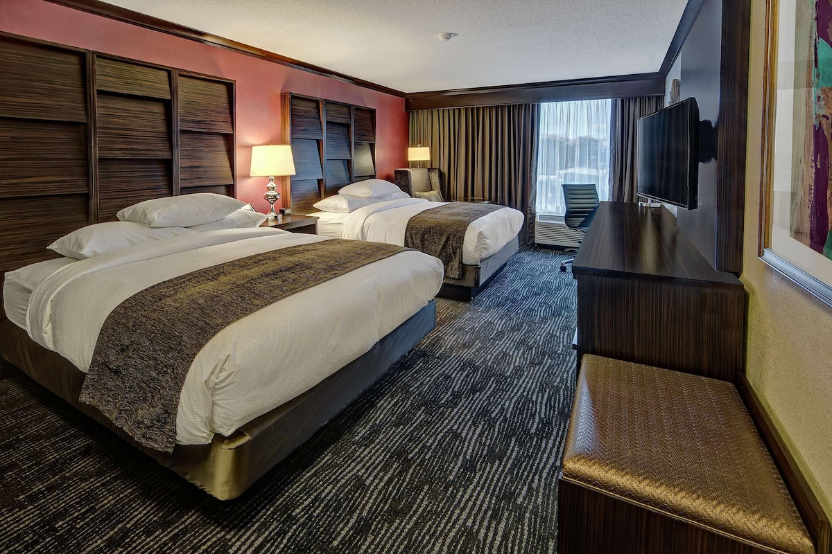 A hotel room with two beds, a TV, and a desk.