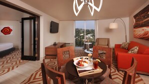 A hotel room with a dining area, a sofa, a TV, and a view of the city. - Hotel Angeleno (Los Angeles)