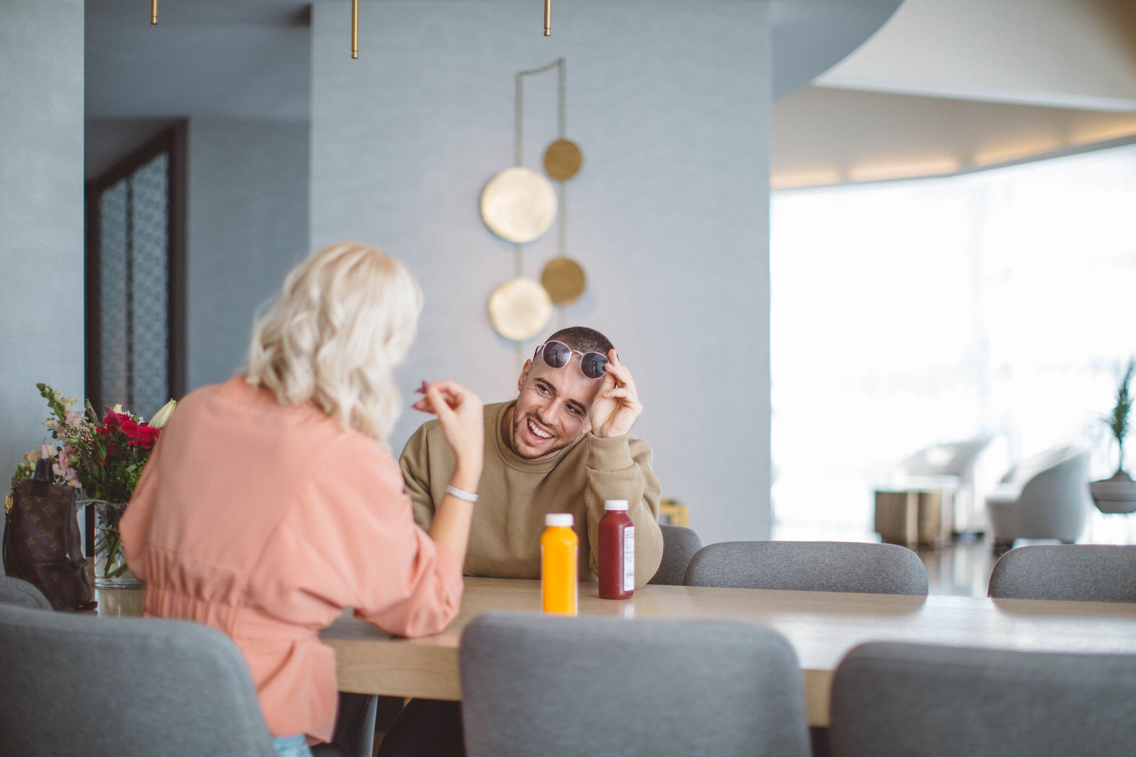 Zwei Personen sitzen an einem Tisch in einem modernen Café mit minimalistischem Design, das eine neutrale Farbpalette und zeitgemäße Einrichtung aufweist.