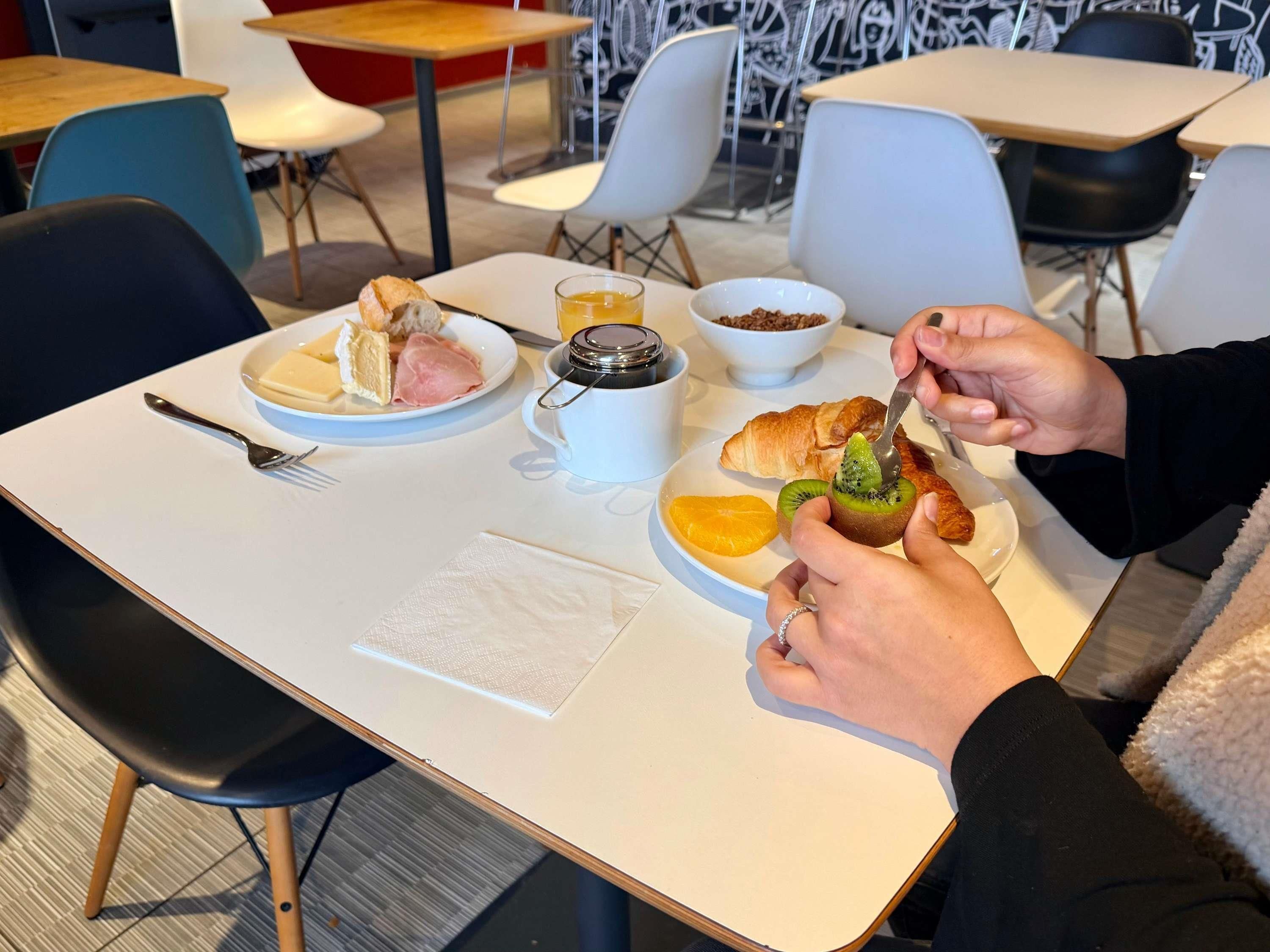 A dining area with tables, chairs, and a person eating a meal.