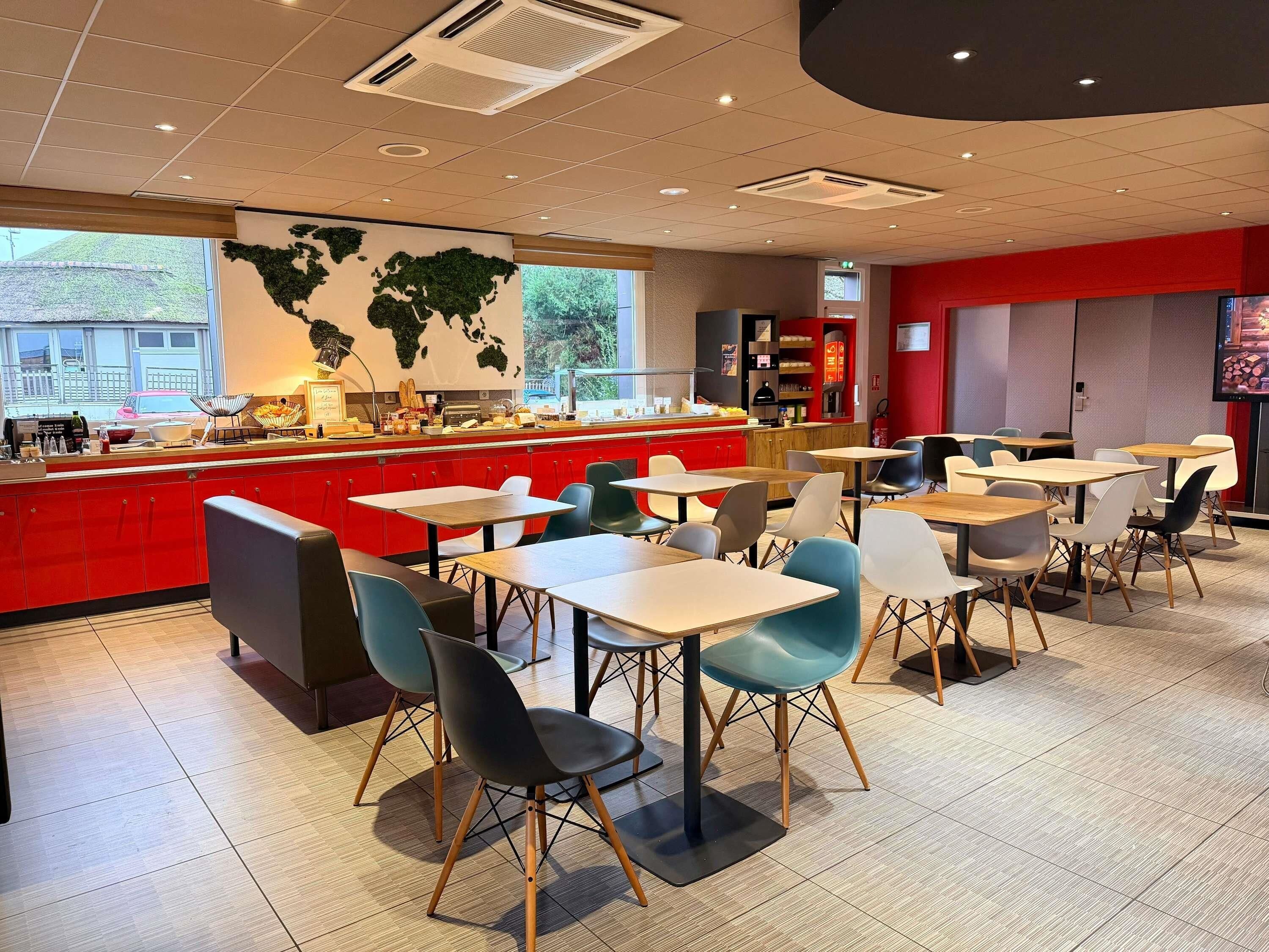 Un restaurant moderne avec un comptoir rouge, de nombreuses tables et des chaises.