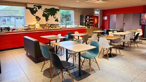 A modern restaurant with a red counter, multiple tables, and chairs. - ibis Rennes Cesson (Cesson-Sevigne)
