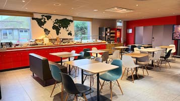 Un restaurant moderne avec un comptoir rouge, de nombreuses tables et des chaises.