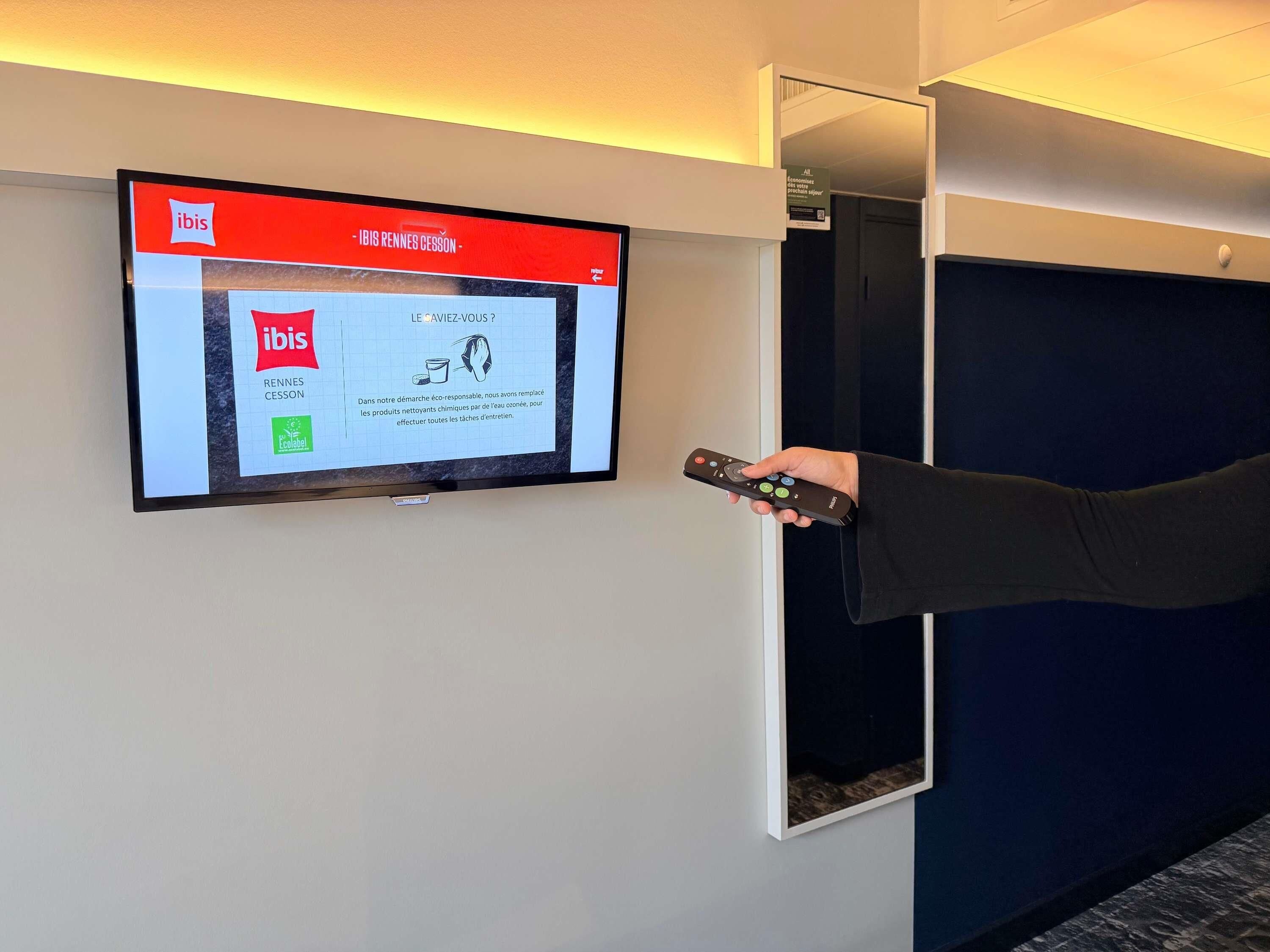 Un téléviseur fixé au mur diffuse une publicité pour ibis, une chaîne hôtelière.