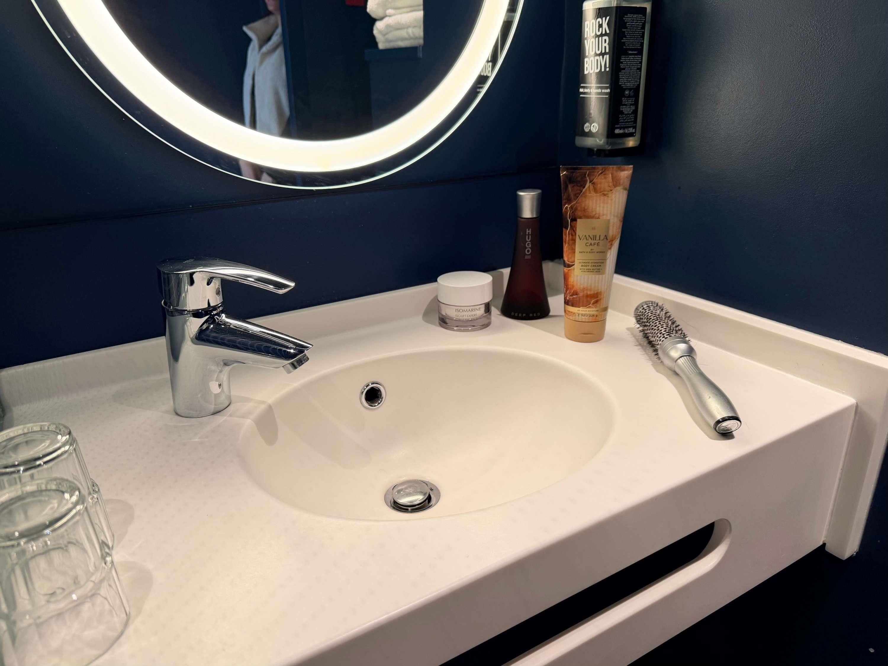 A bathroom sink with a mirror, a toothbrush, and toiletries.