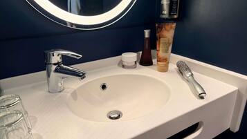 A bathroom sink with a mirror, a toothbrush, and toiletries.