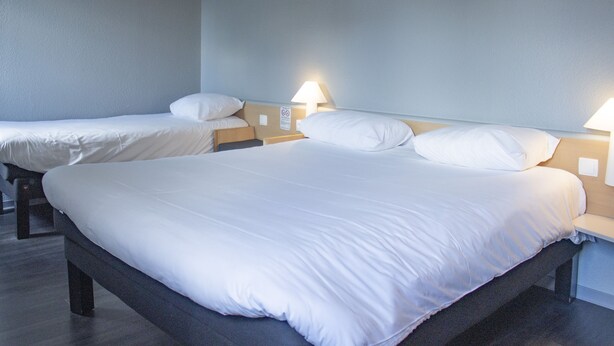 A hotel room with two single beds, each with a nightstand and a lamp. - ibis Rennes Cesson (Cesson-Sevigne)